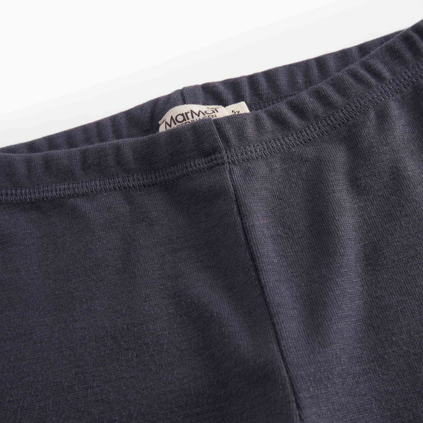 Close-up of dark gray pants with a brand label on a white background