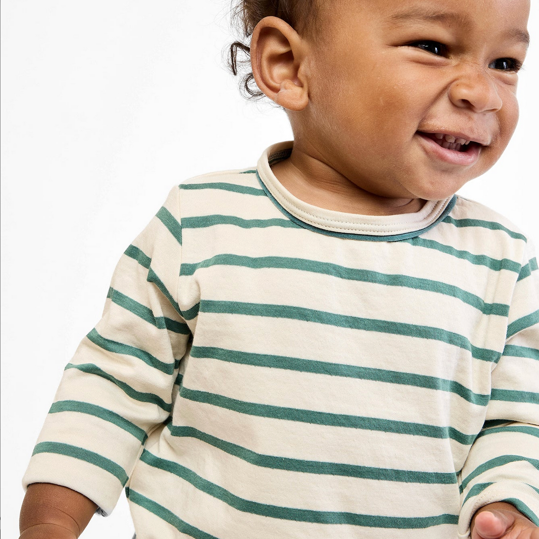 Child wearing a striped shirt with green and white horizontal stripes on a plain background