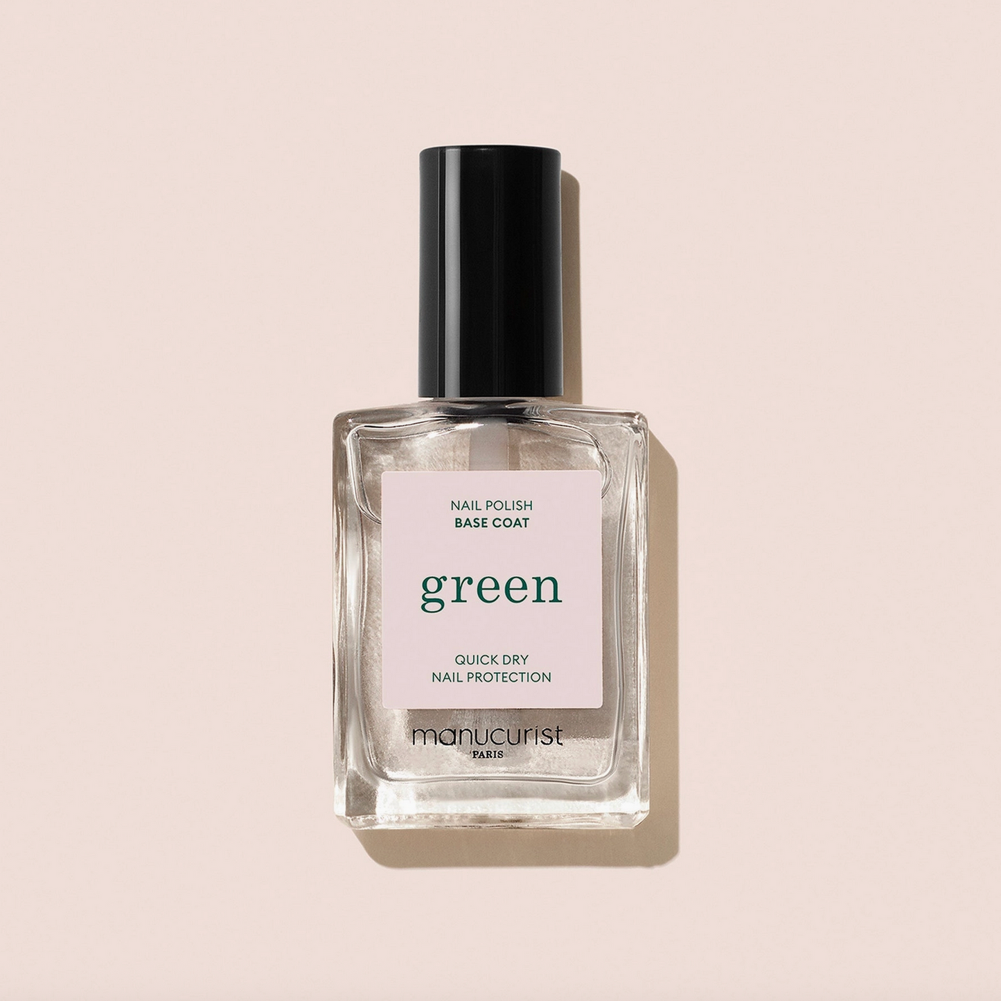 Bottle of nail polish base coat labeled 'green' on a beige background