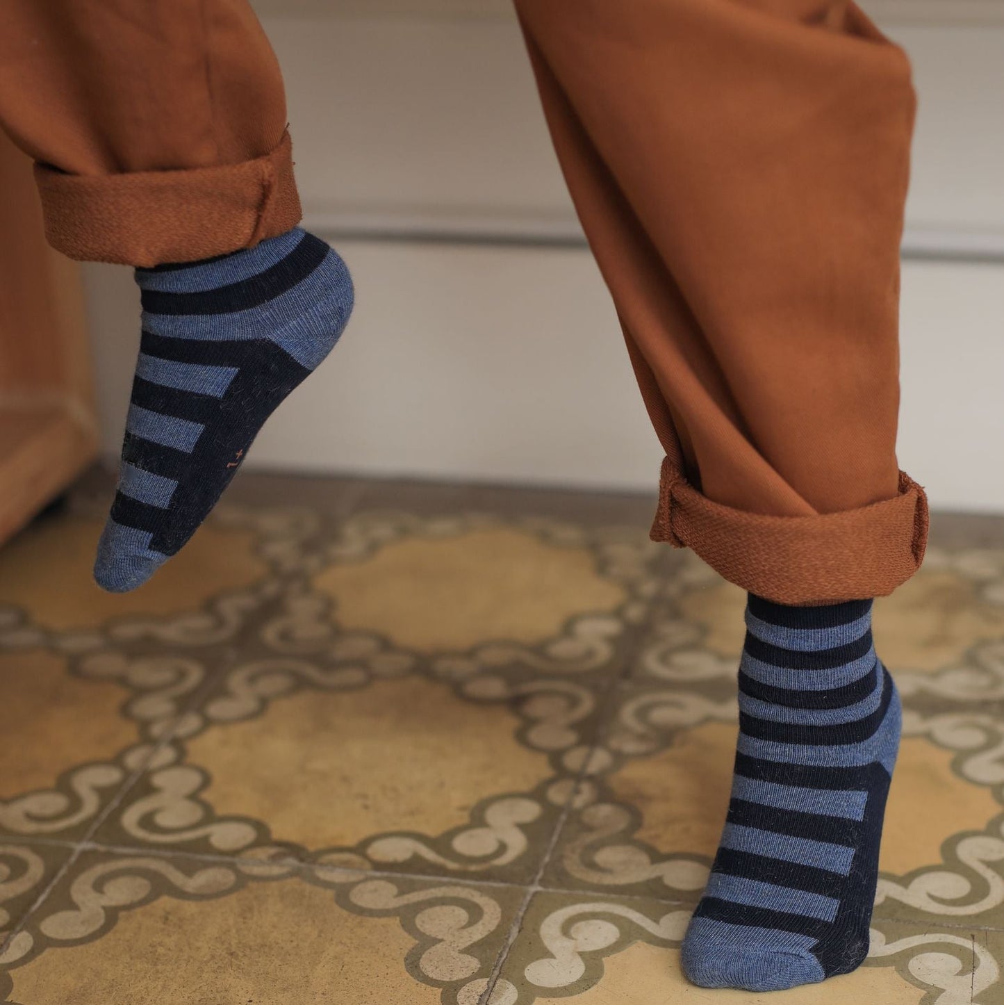 Person wearing blue striped socks on a patterned floor