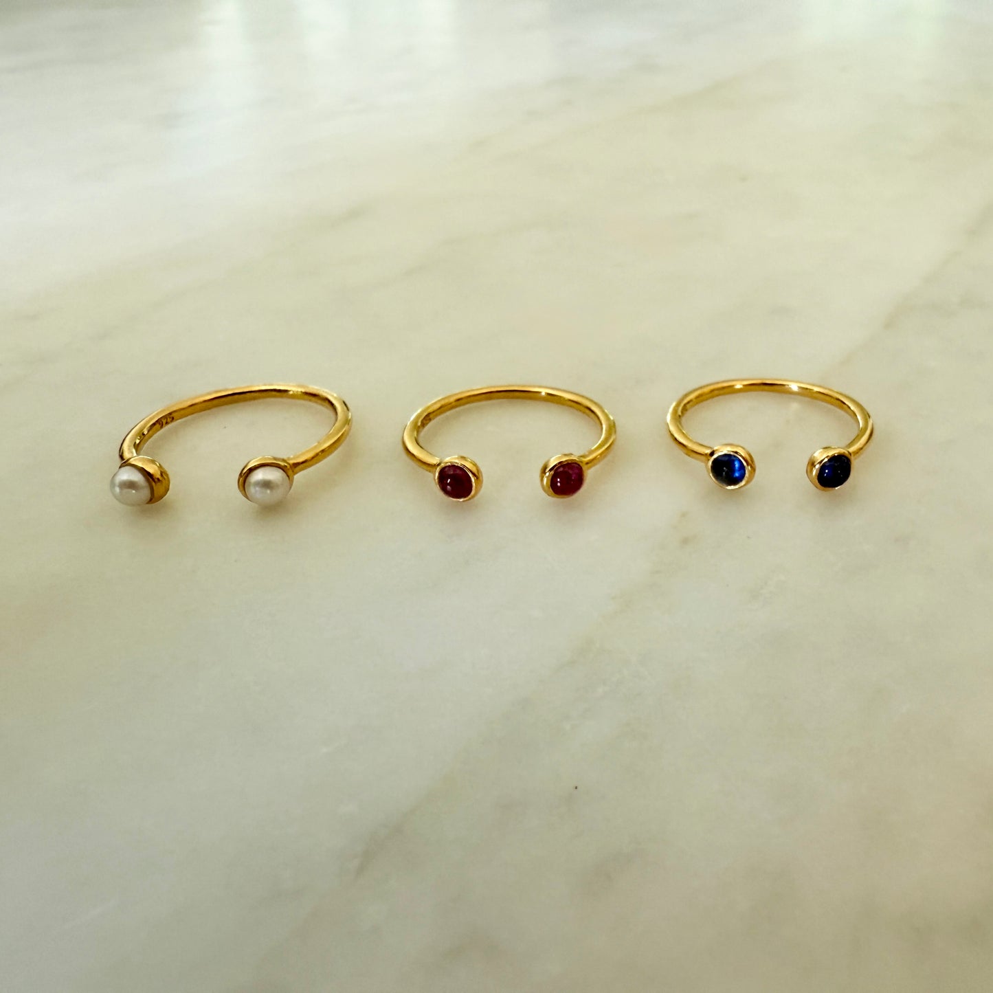 Three gold nose rings with gemstones on a light background