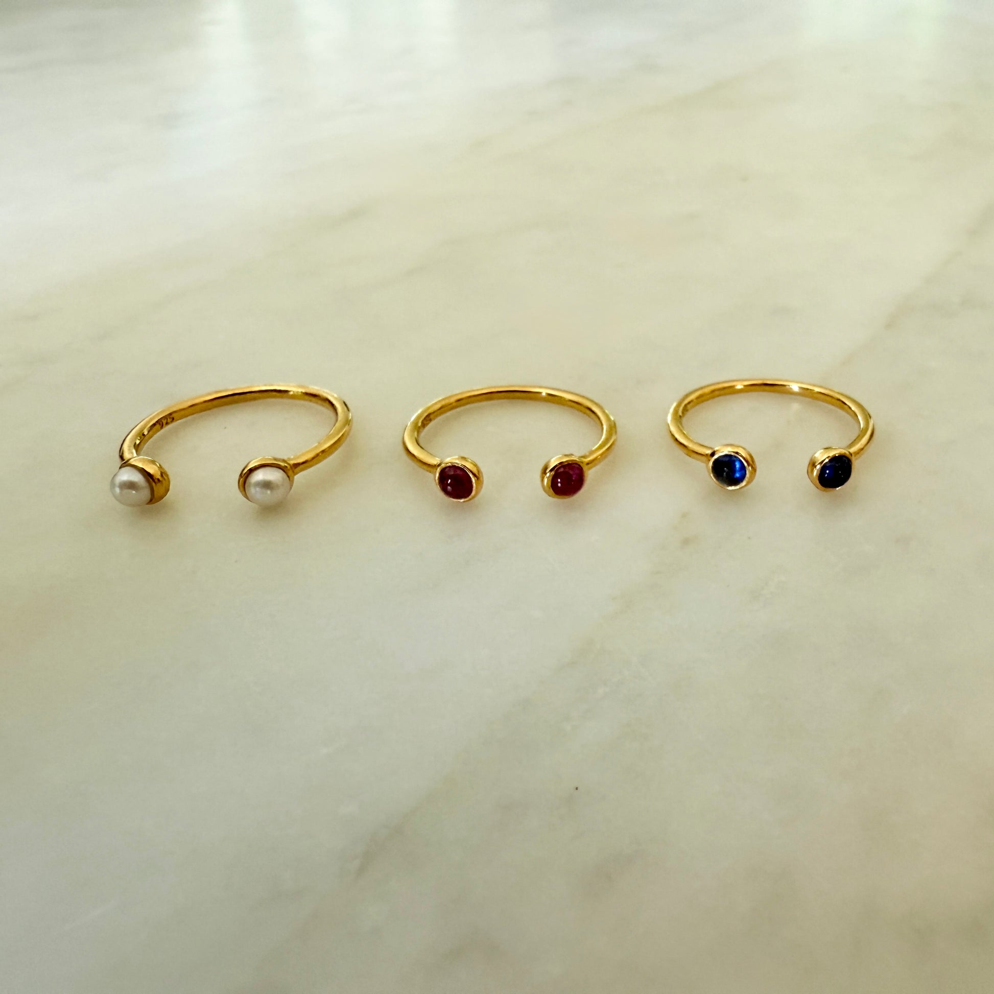 Three gold nose rings with gemstones on a light background