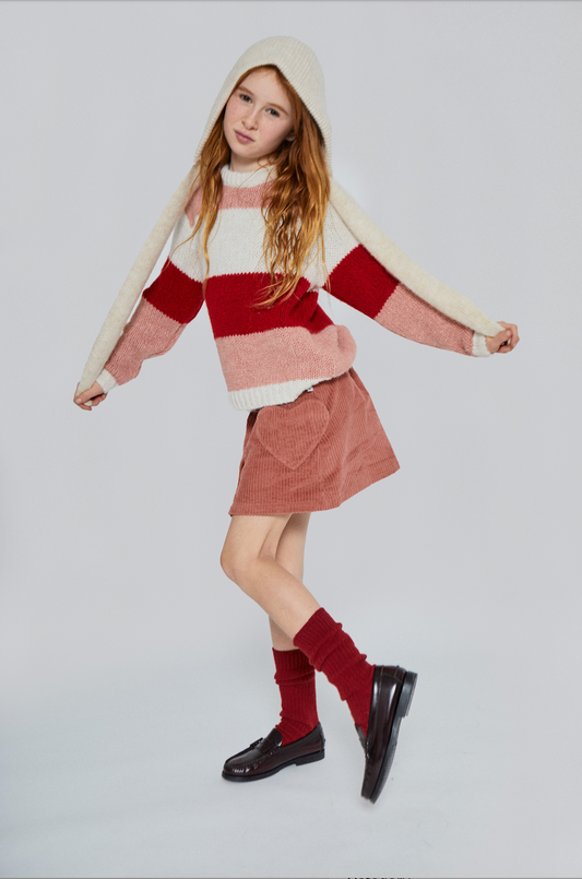 Person wearing a striped sweater, skirt, and knee-high socks on a white background