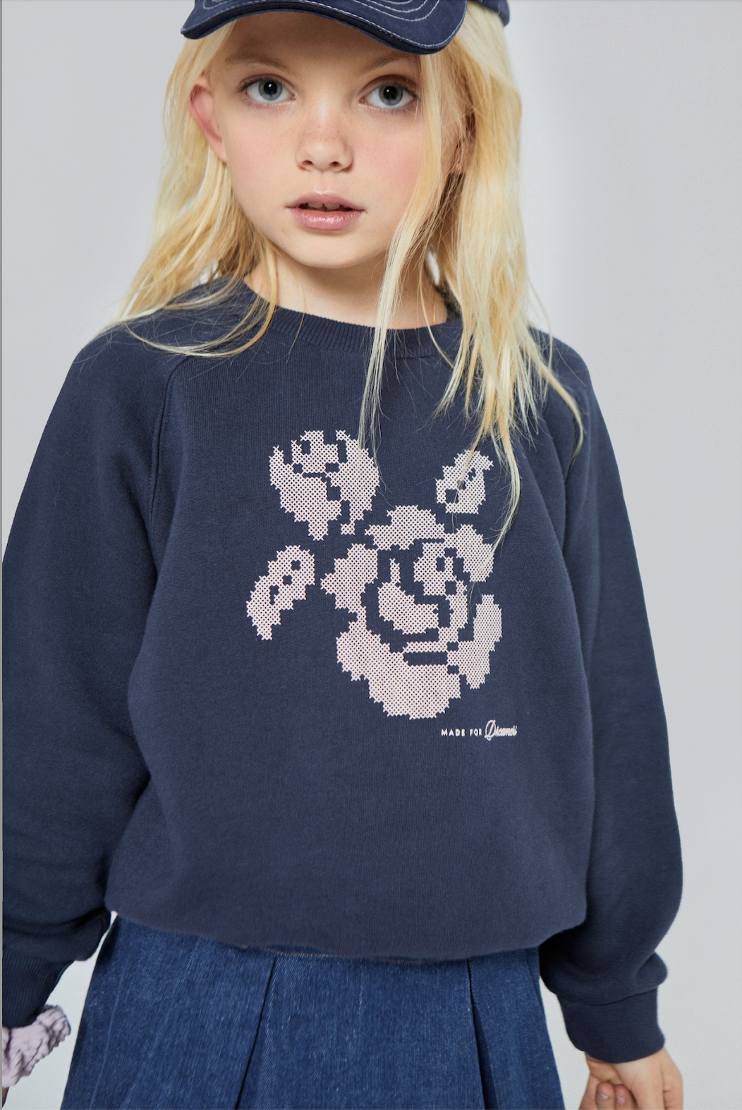 Child wearing a navy sweatshirt with a graphic design on a plain background