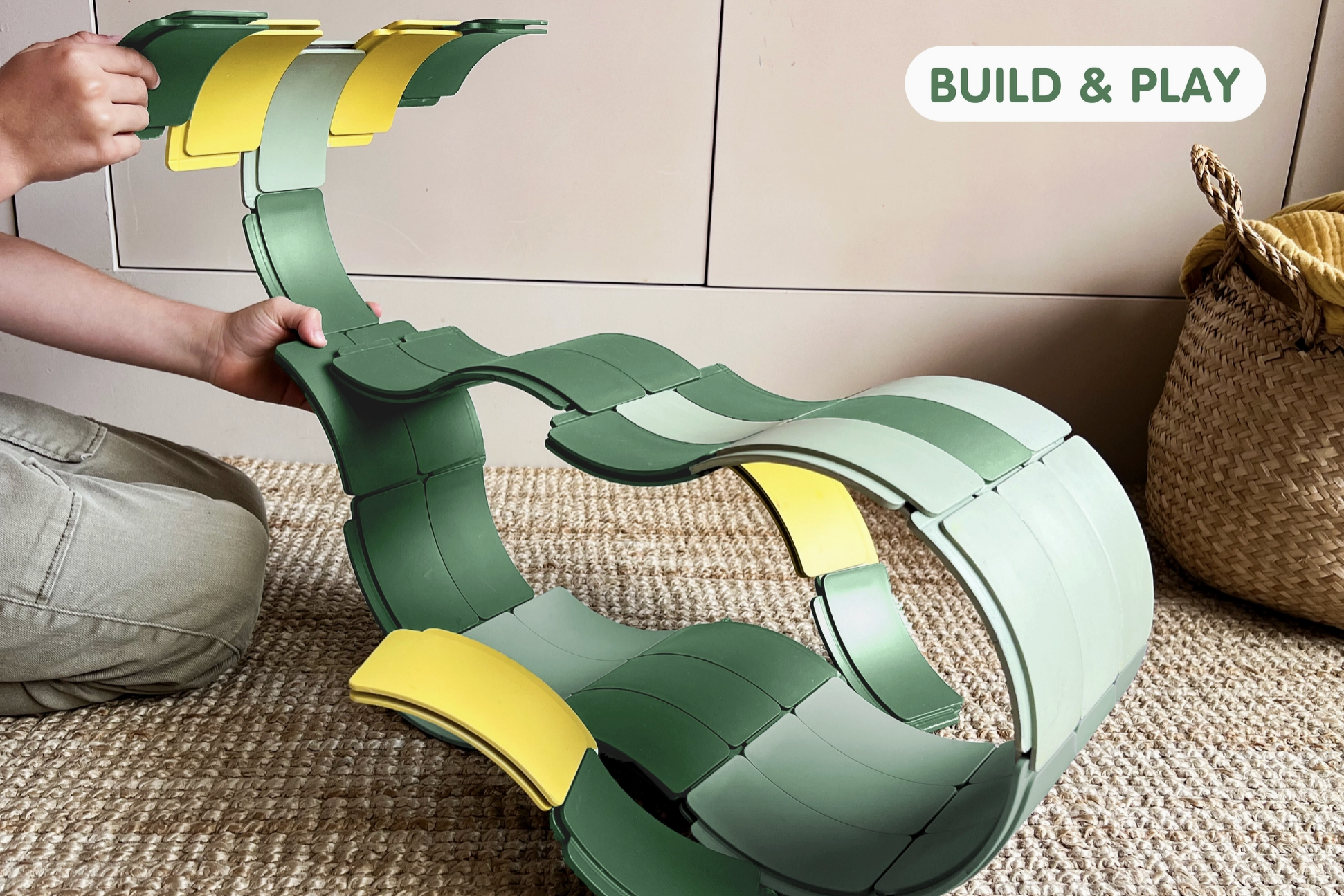 Child building a green and yellow structure with interlocking pieces on a carpeted floor.