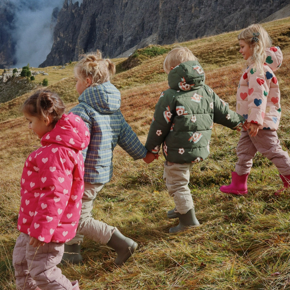 Four children holding hands in a mountainous landscape