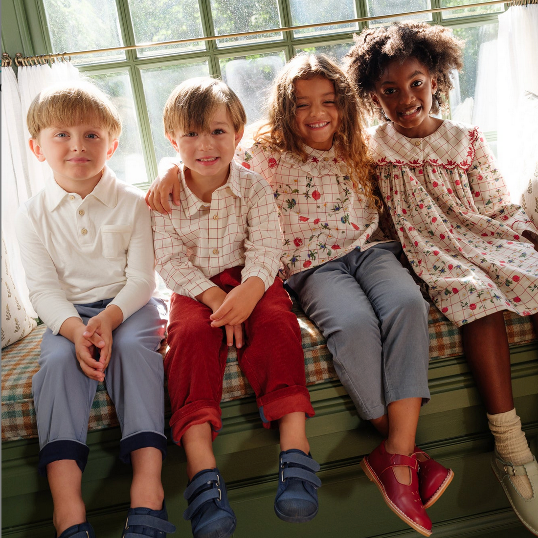 Four children sitting on a window sill with a bright and cheerful atmosphere.
