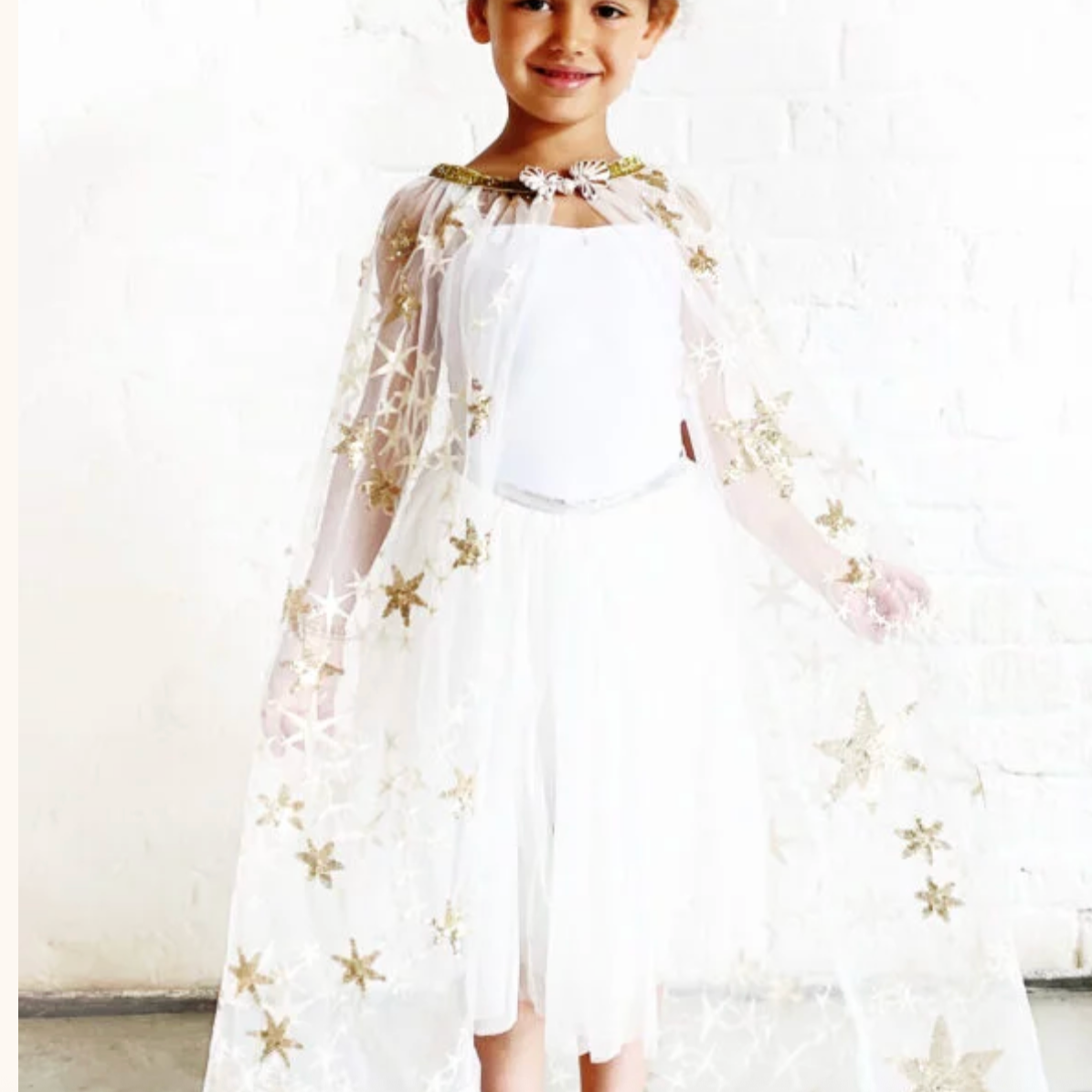 Child wearing a white dress with gold star patterns on a plain background