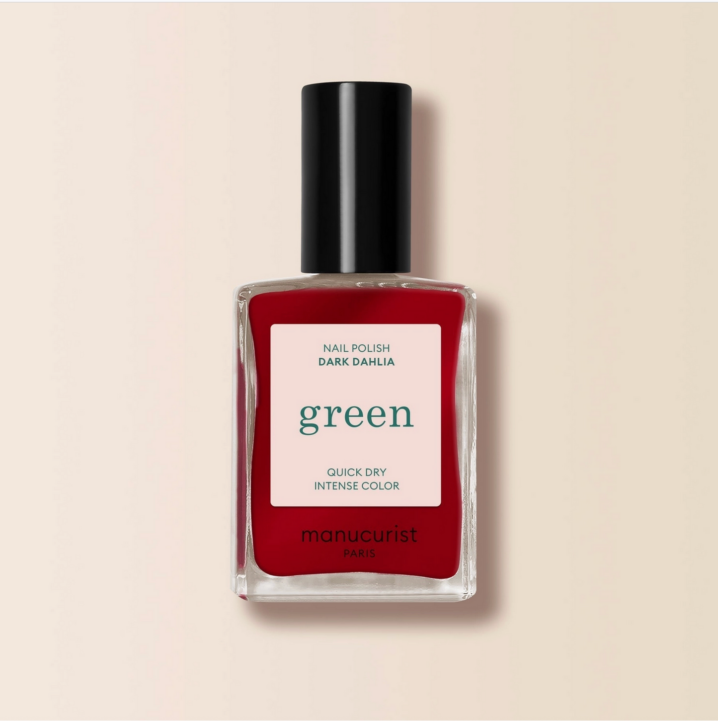 Red nail polish bottle with a black cap on a beige background