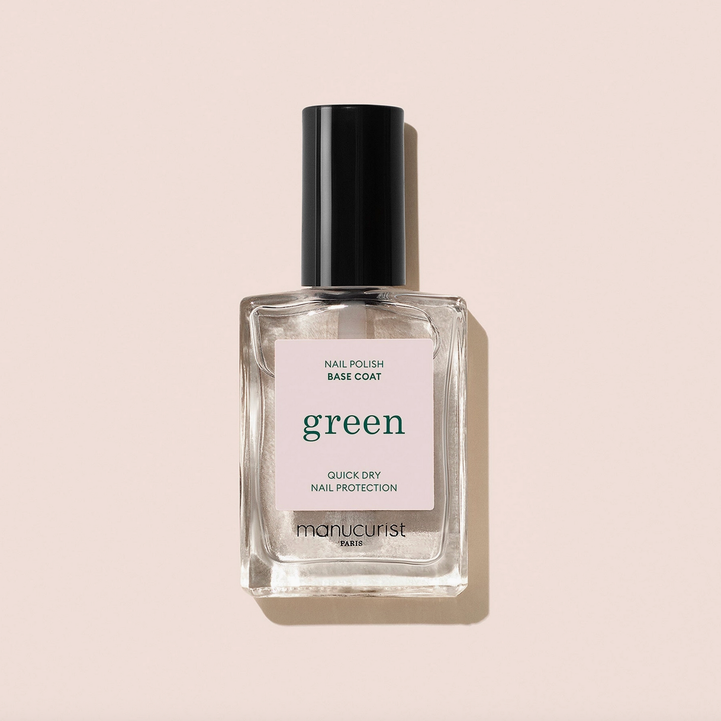 Bottle of nail polish base coat labeled 'green' on a beige background