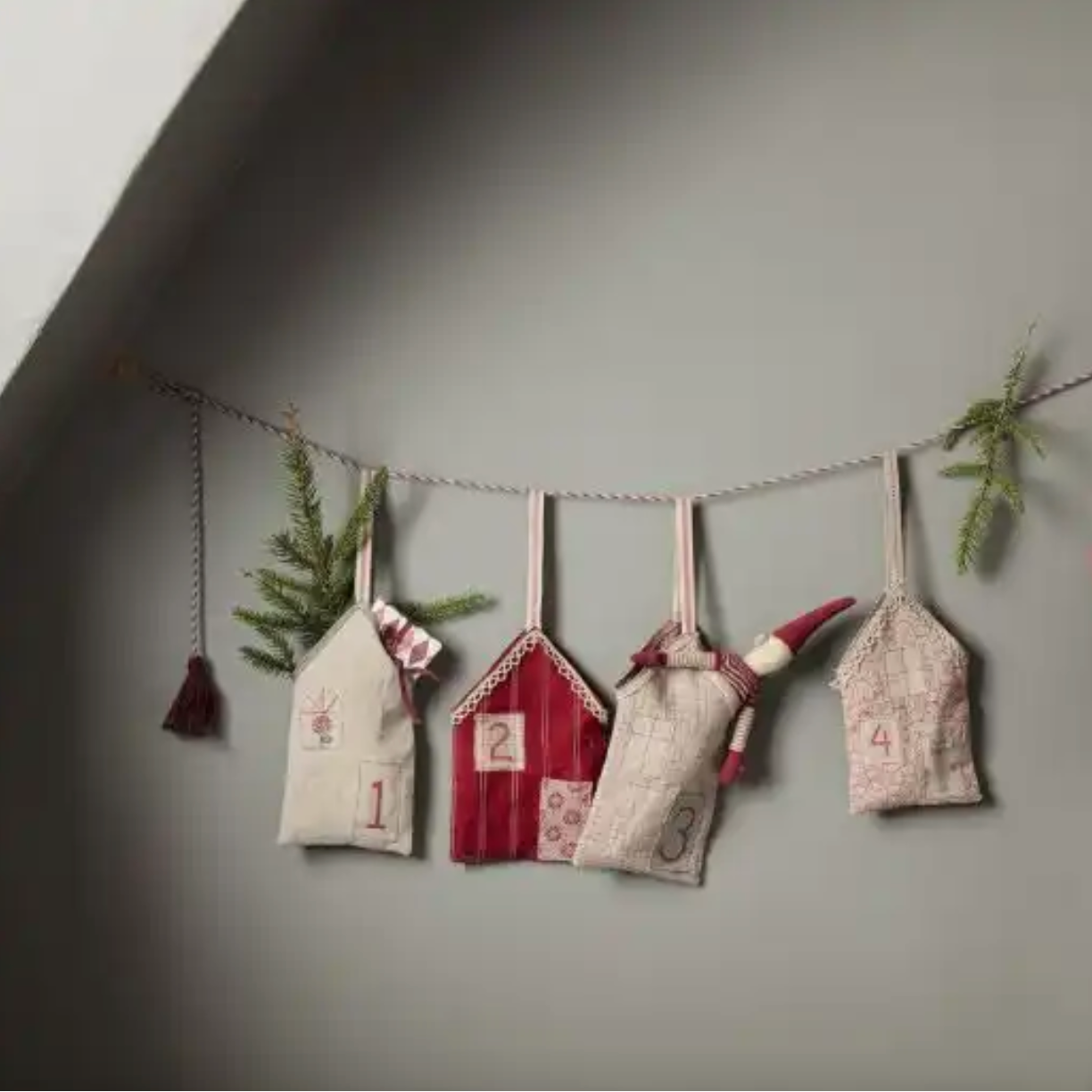Decorative advent calendar with small houses and numbers on a gray wall.