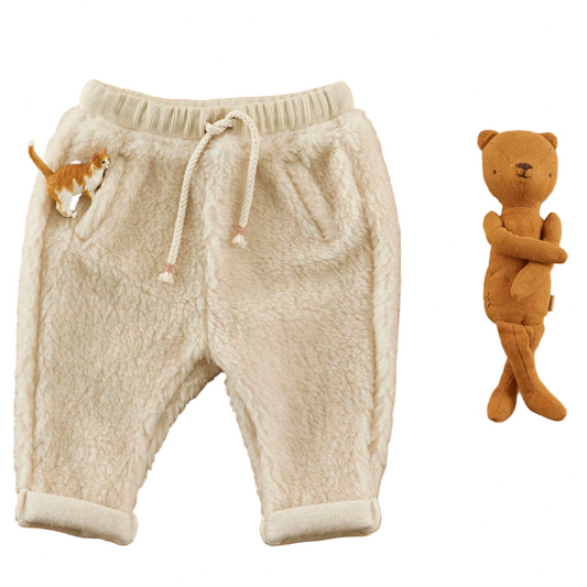 White fleece baby pants with a teddy bear on a beige background