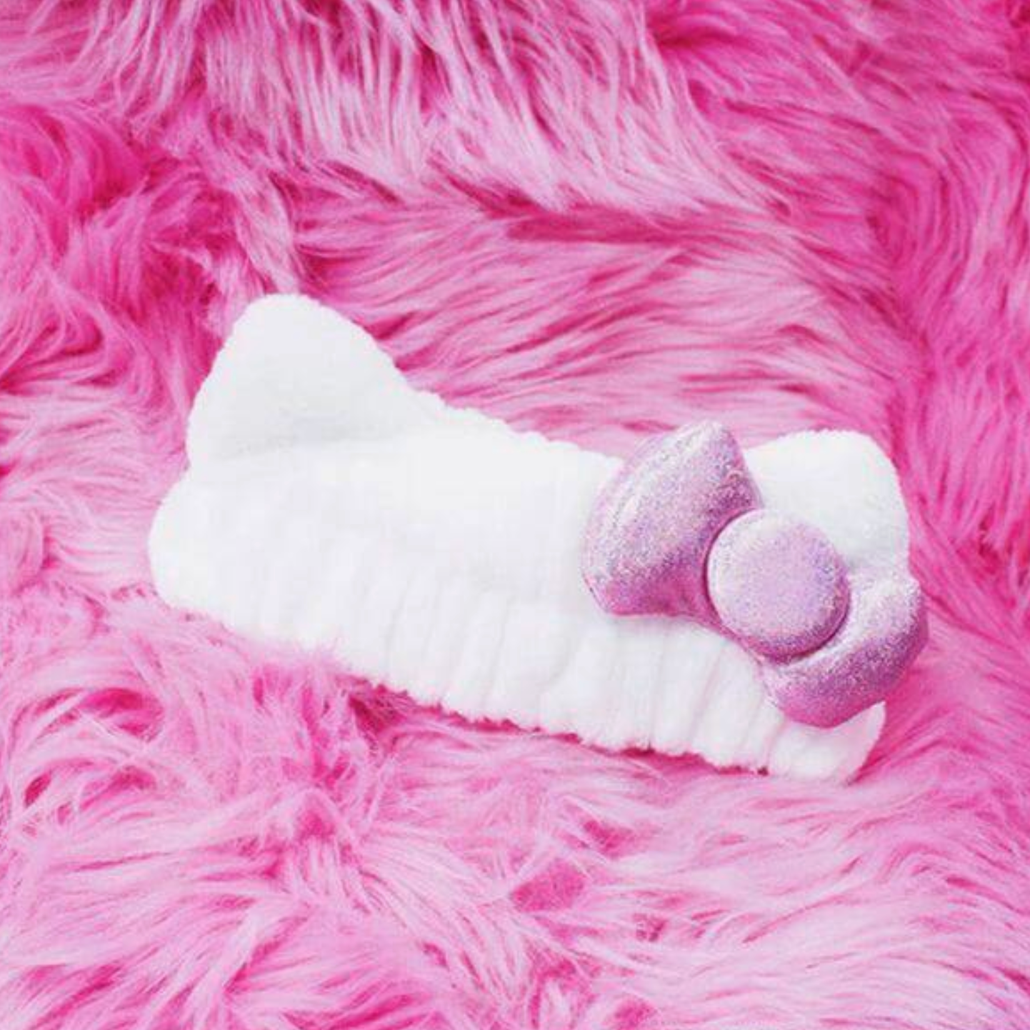 White and purple bow toy on a pink fluffy surface
