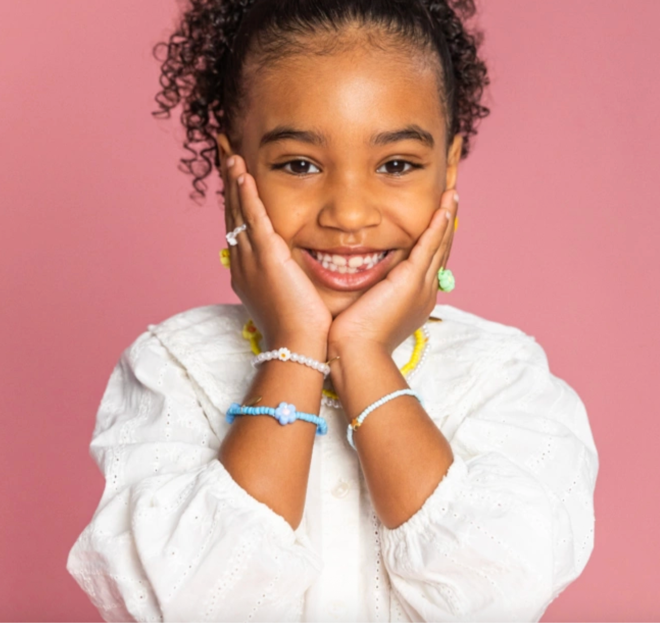 Young girl with hands on cheeks against a pink background